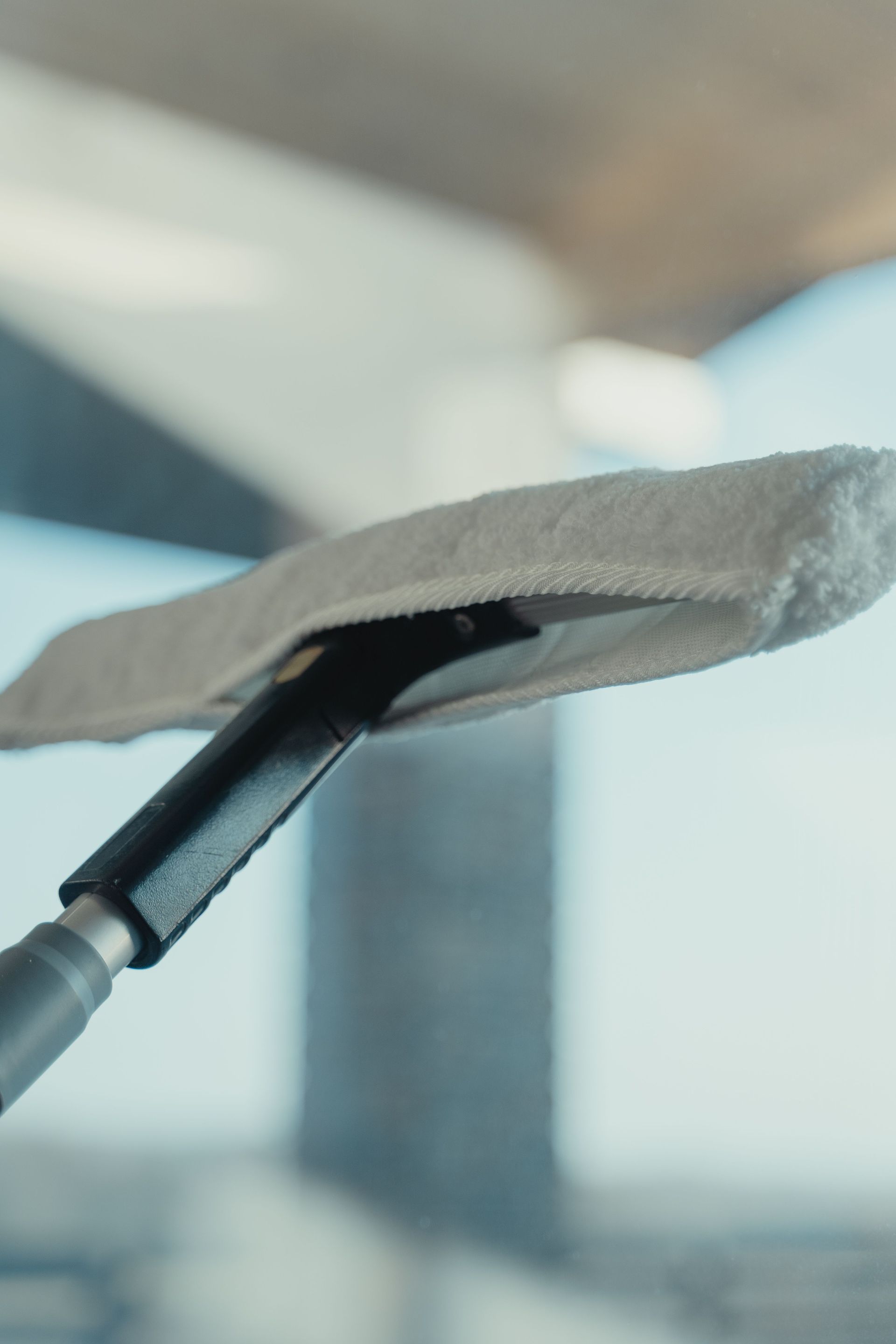 Close-up of a cleaning tool on a window showcasing maintenance and sanitation.